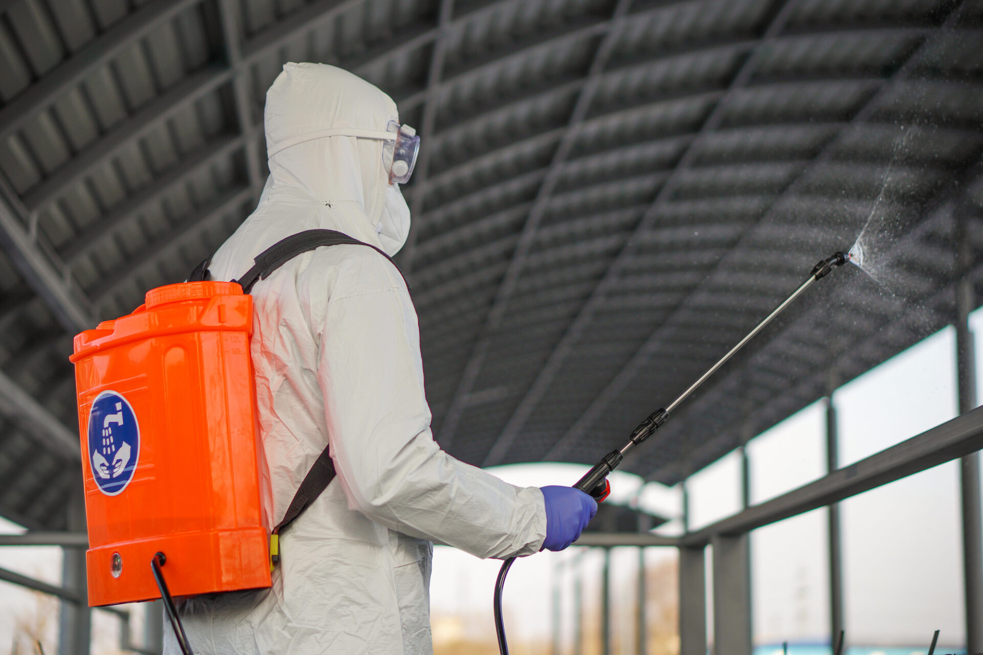 worker in ppe spraying disinfectant to combat covid 19